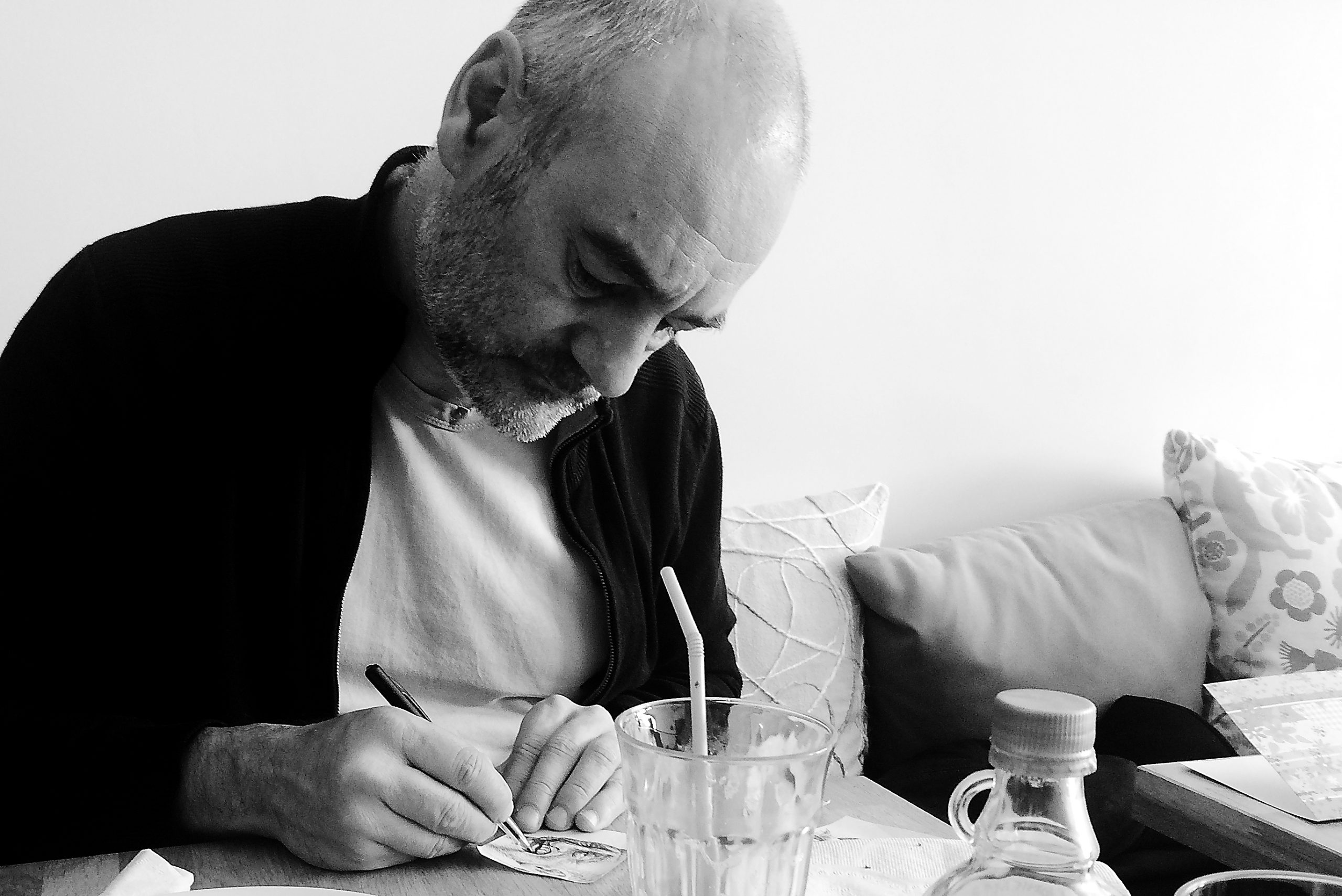 Portrait de Stéphane Neidhardt, dessinant sur un coin de table.